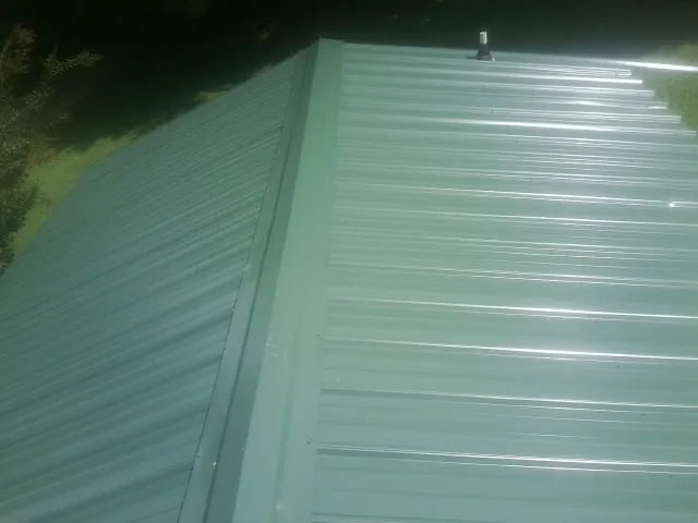 New green metal panels meeting at the ridge of a roof — Flat Roof Repair work by our crew in Marne